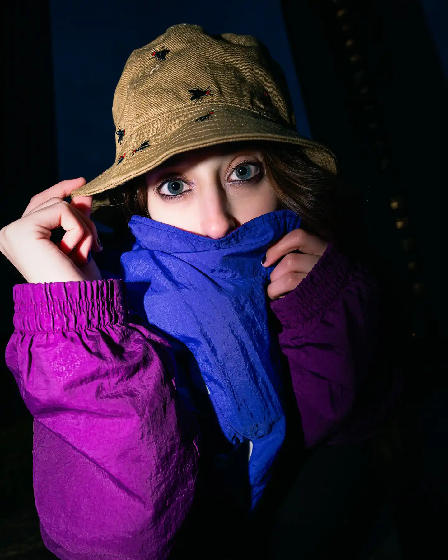 A girl poses with a bucket hat and windbreaker for a upclose shot.